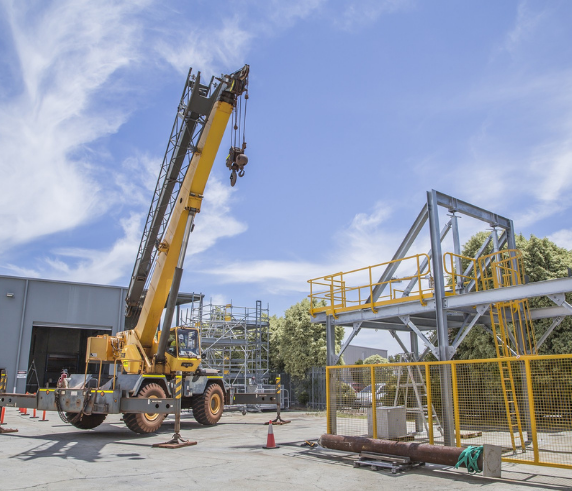 C1 Crane being operated at a warehouse facility with scaffolding structure in the background.