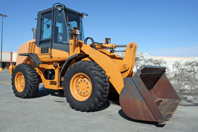 Conduct Civil Construction Wheeled Front End Loader Operations. Orange wheeled front-end loader with a large bucket, ready for operation on a civil construction site