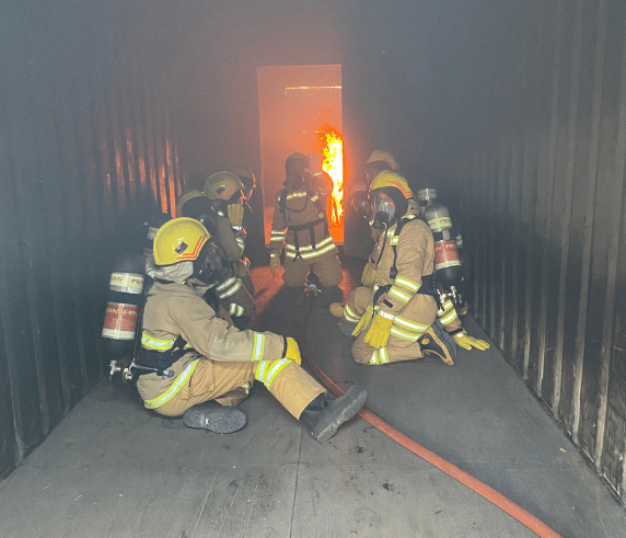 Firefighting trainees in full gear operating breathing apparatus during a live fire training exercise at Saferight Welshpool facility during Emergency Response and Rescue Module 1 course.