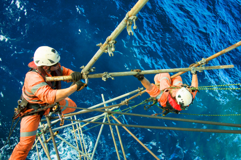 Two harnessed scaffolded workers working safely from heights building scaffolding over the open ocean as part of the Intermediate and Advanced Scaffolding Course Perth WA