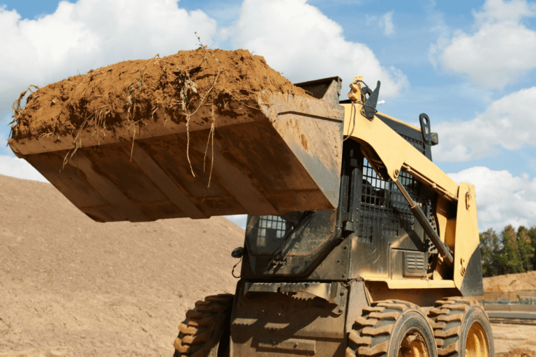 conduct civil construction skid steer loader operations. Skid steer loader lifting a full bucket of earth on a construction site