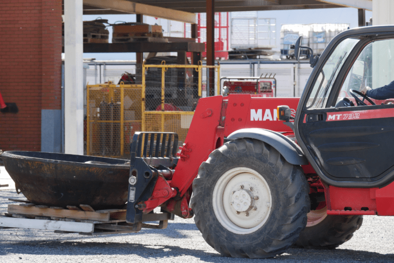 Telehandler being used by trainee moving a large tire on a wooden pallet at Saferight training facility.