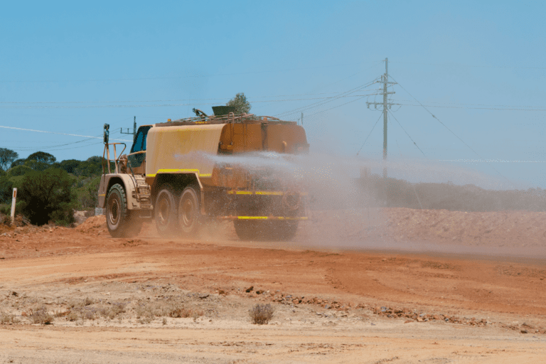 Conduct Water Vehicle Operations. A water truck spraying to control dust on a dry and dusty construction site