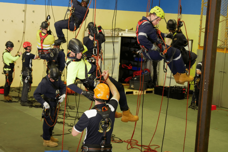 Trainees practicing safety inspections on height safety equipment during an indoor training course