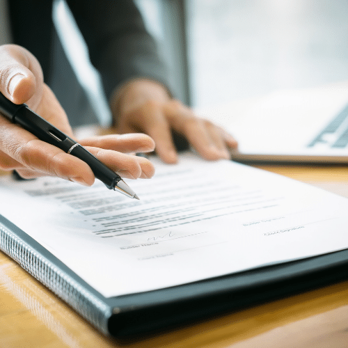 Man holding his hand out in an open palm holding a black pen pointing at a Supervised work permit document.