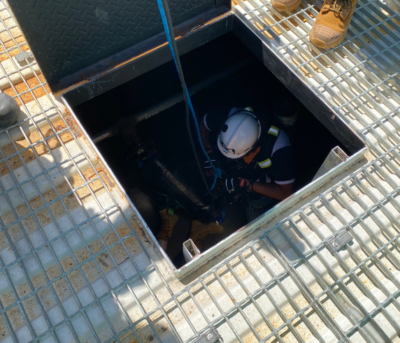 Confined Space Entry Supervisor. Trainee in protective gear descending into a confined space during a supervisor training course