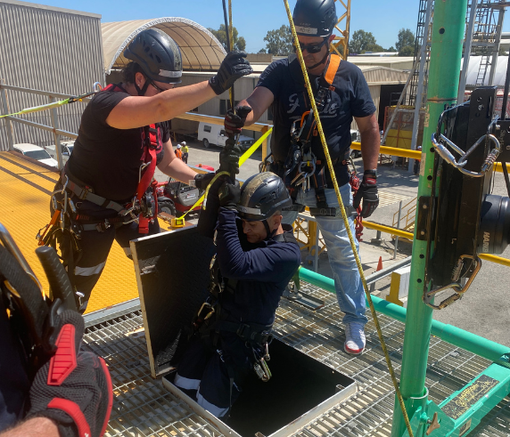 Confined Space Entry. Trainee in protective gear descending into a confined space during a supervisor training course
