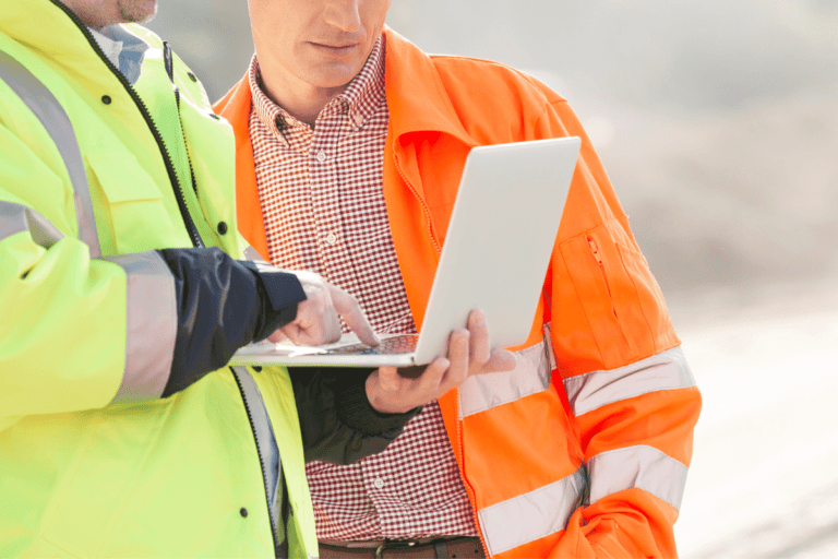 Apply WHS Policies and Procedures in the Construction Industry. Two construction workers consulting a digital tablet while reviewing WHS policies on site