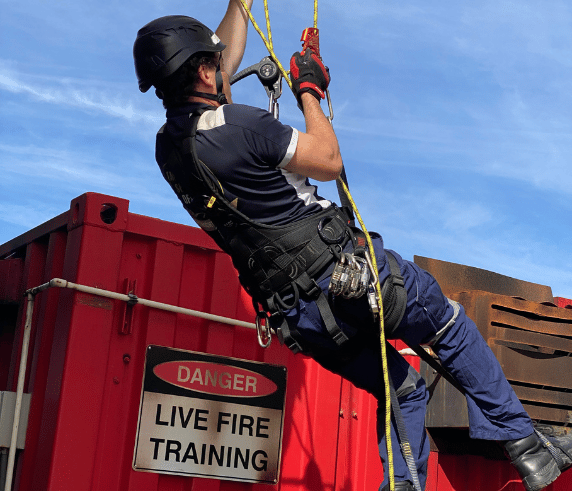 A trainer harnessed and suspended from a structure outdoor participating in Saferight's Working Safely From Heights course delivered at Saferights training facility.