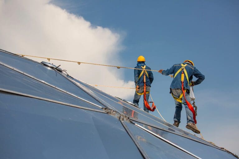 Male two workers rope access height safety connecting with eight knots safety harness, clipping into roof fall arrest and fall restraint anchor point systems ready to ascending, construction site oil tank dome.