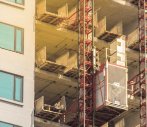 Materials hoist attached to the side of a construction building for Material Hoist Perth - Hoist Operator Training Course