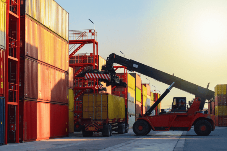 A reach stacker lifting a yellow cargo container at a container terminal
